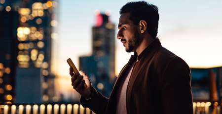 Cityscape at sunset with man looking at his mobile