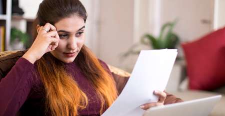 Menyw gyda gliniadur yn darllen bil