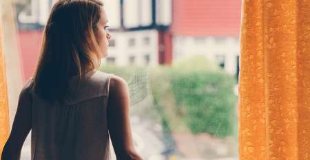 Merch ifanc yn syllu allan o ffenestr yn meddwl am ei dyledion