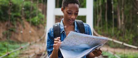 Woman in rural surroundings looking at travel map on bridge.