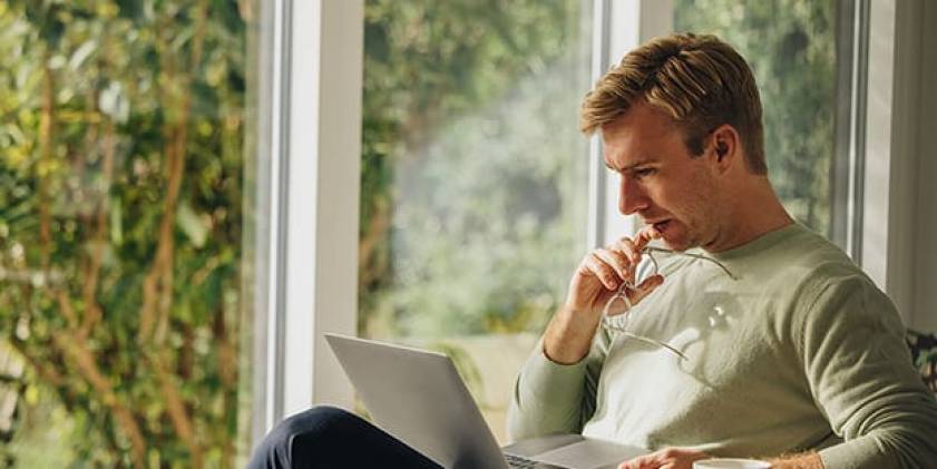 Man sitting in chair at home with laptop