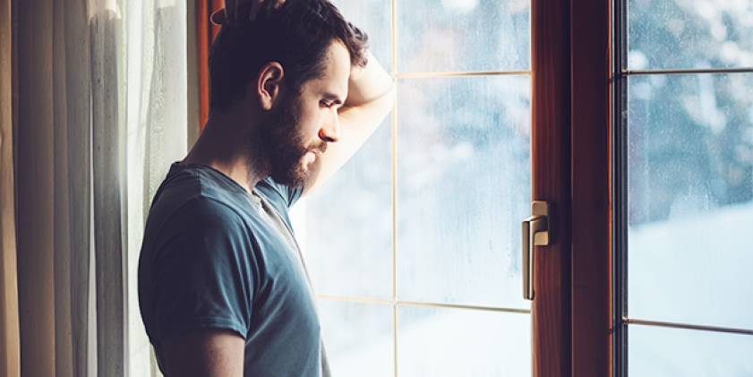 Man standing by window looking down