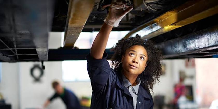 Woman mechanic fixing car from underneath