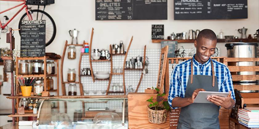 Dyn ifanc yn edrych ar ipad yn gwenu